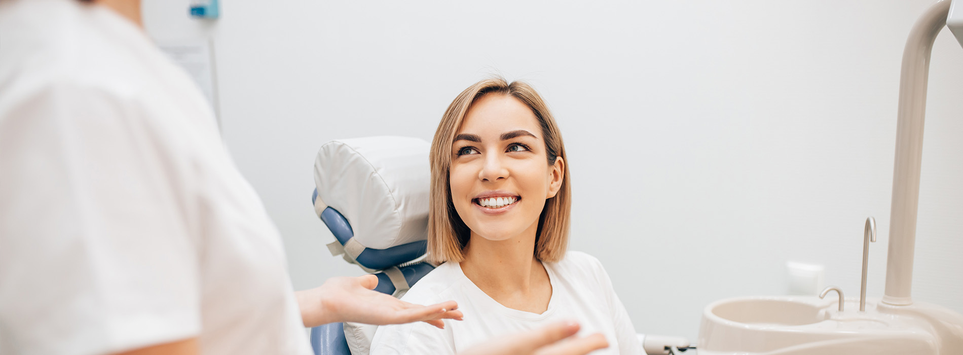 The image shows a dental professional interacting with a patient in a clinical setting.