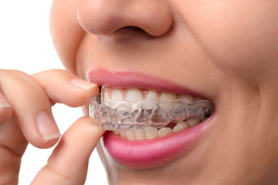 The image shows a person with a smile, holding a toothpaste tube and seemingly brushing their teeth.