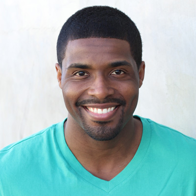 Two elderly adults, a man and a woman, smiling and embracing each other outdoors.