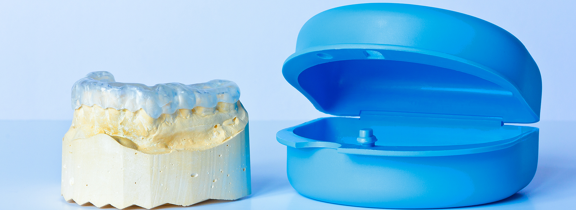 The image features a side-by-side comparison of a dental implant and its corresponding model, with the implant on the right being a solid, white tooth-like structure and the model on the left being a blue, plastic representation.