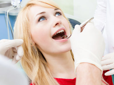 A woman receiving dental care with a smile, seated in a dental chair while a dentist works on her.